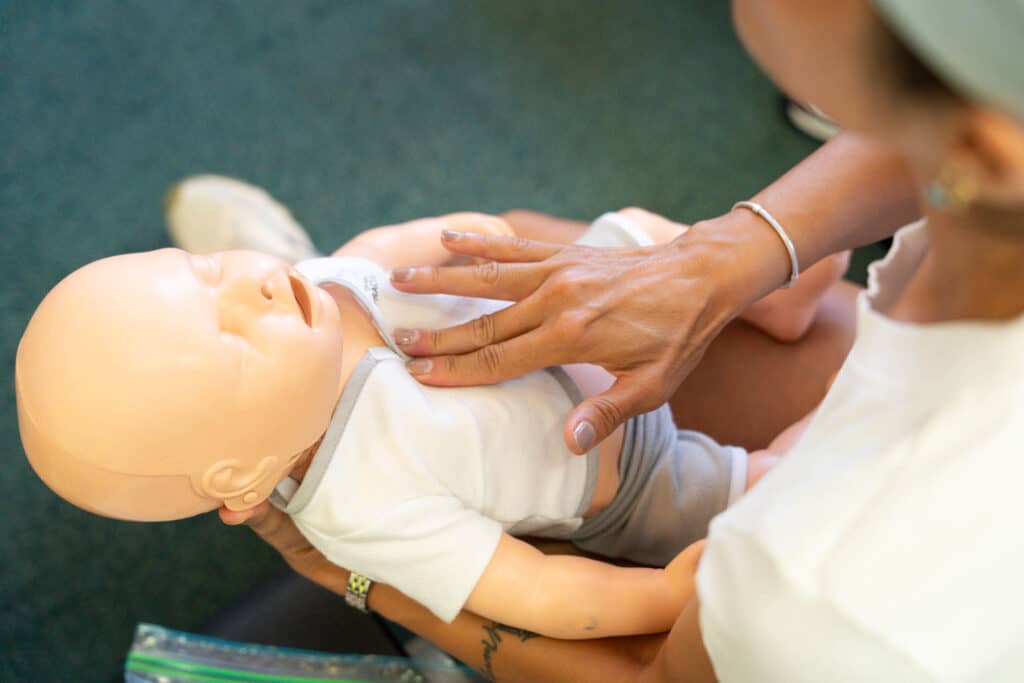 Person practicing CPR on baby mannequin